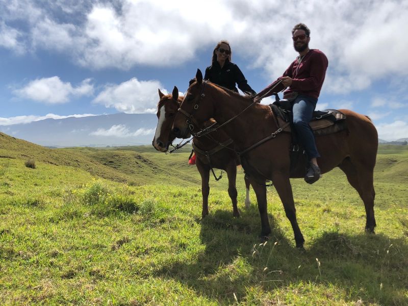 Horseback Riding on a Grassy Hillside Under a Cloudy Sky